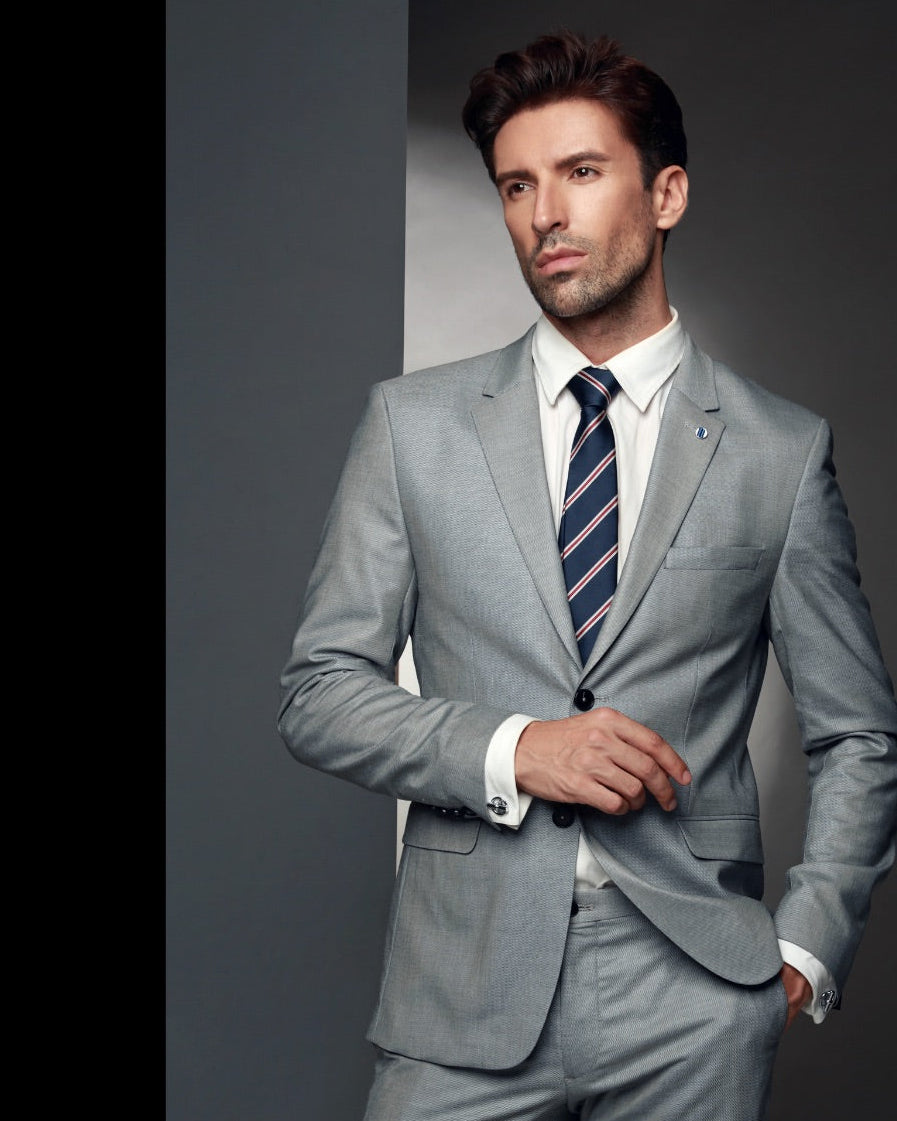 Man wearing a gray suit with a striped tie against a dark background
