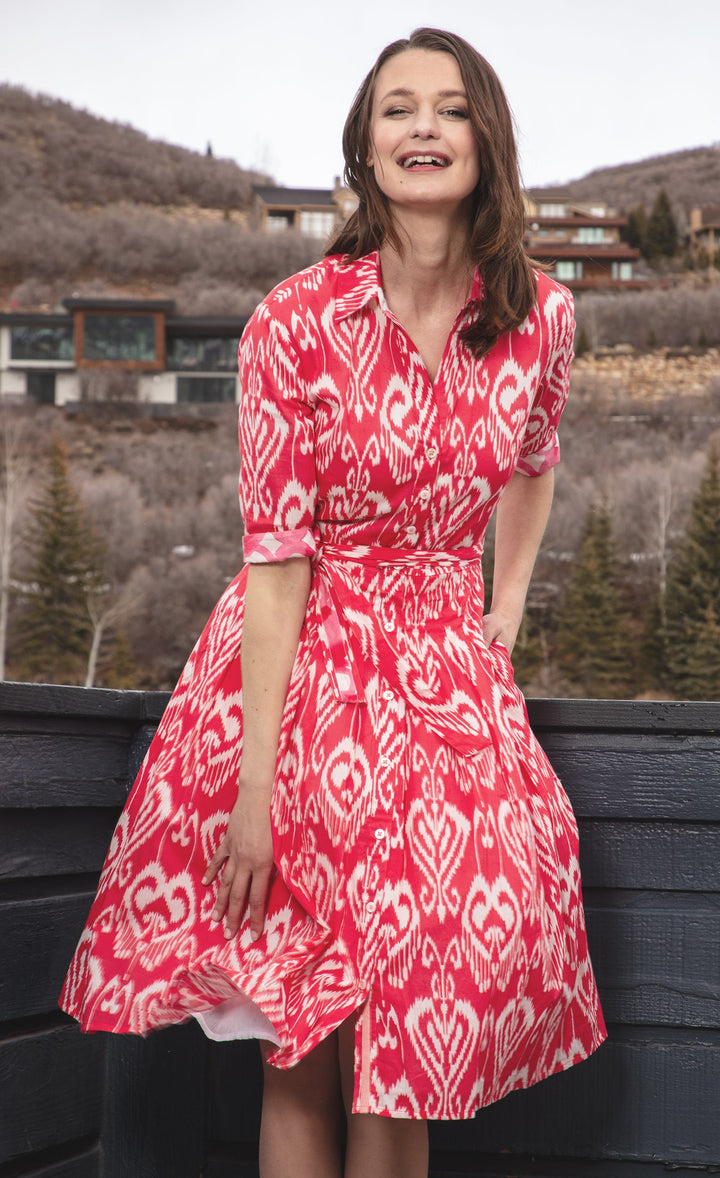 Woman wearing a red and white patterned dress standing outdoors with mountains in the background