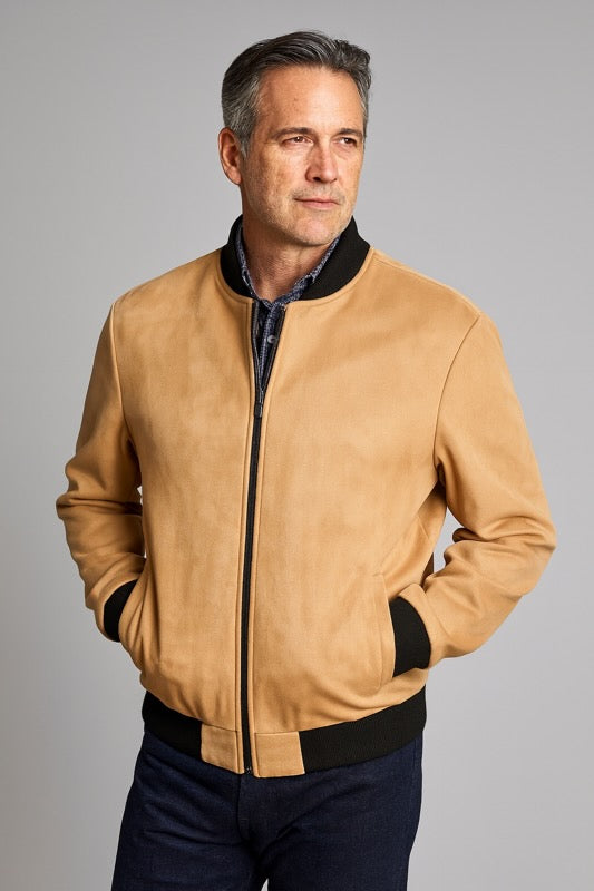 Man wearing a tan leather jacket with black accents on a gray background